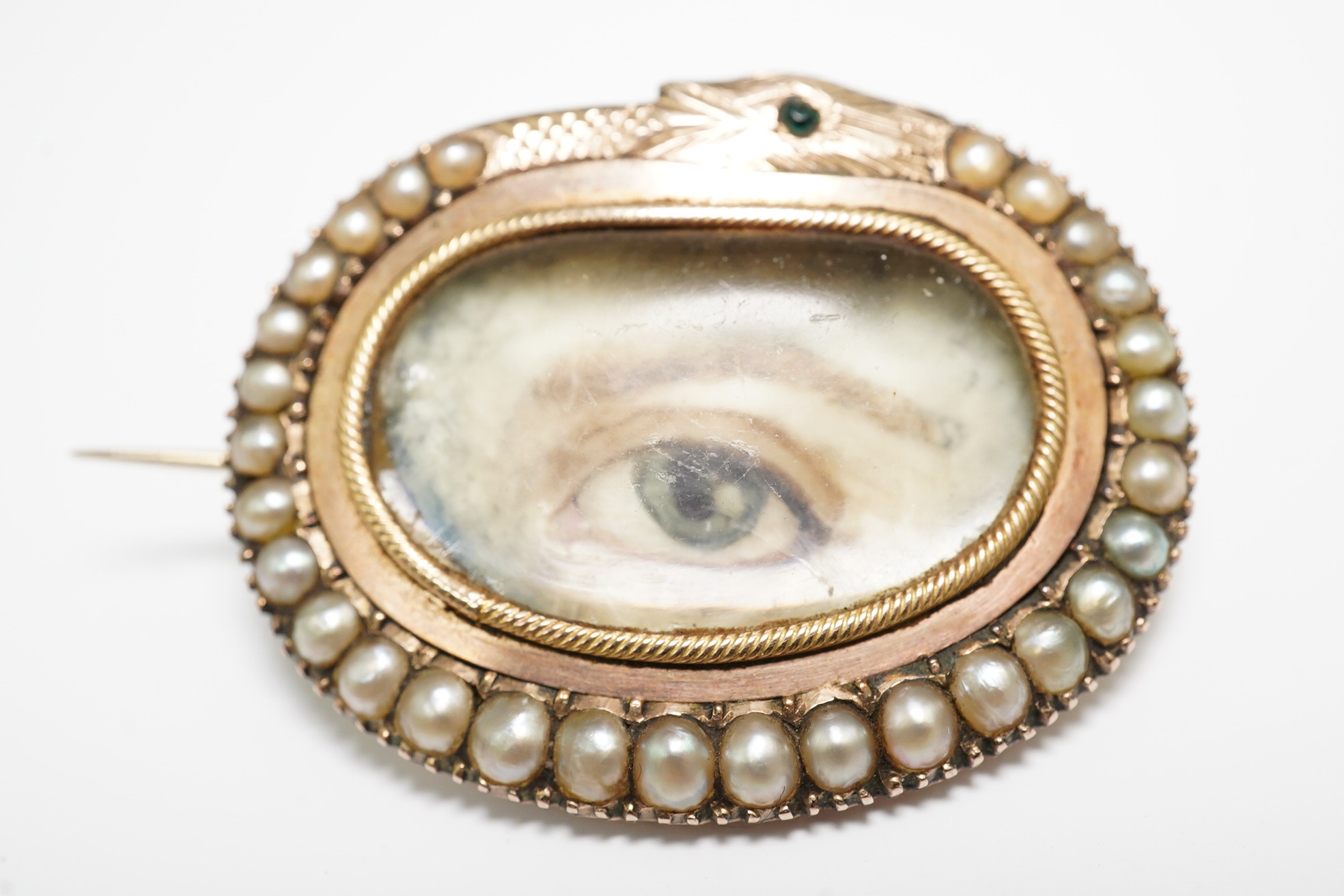 A Regency gold and split pearl mounted oval pendant brooch with inset 'lover's eye' miniature